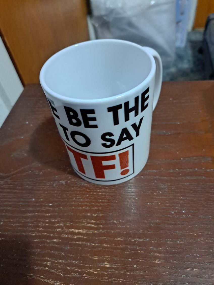 White coffee mug with bold black and red funny typography coffee mug text on a wooden surface